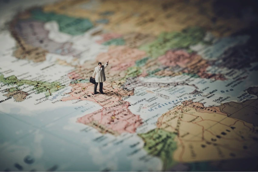 Miniature business figure standing on a world map, representing location selection