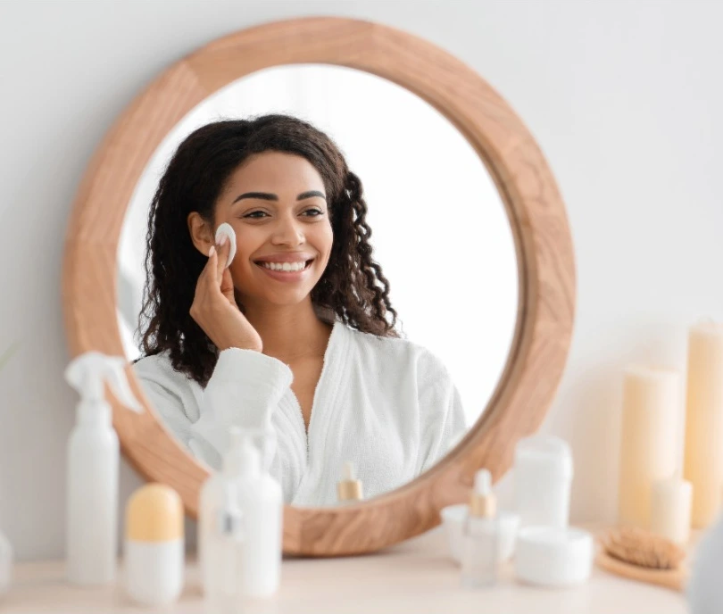 Person applying skincare product while looking in a round mirror