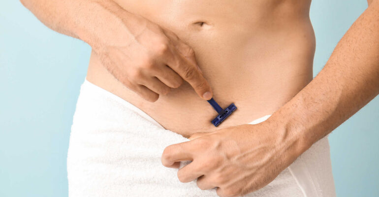 Handsome young man shaving his body on color background, closeup